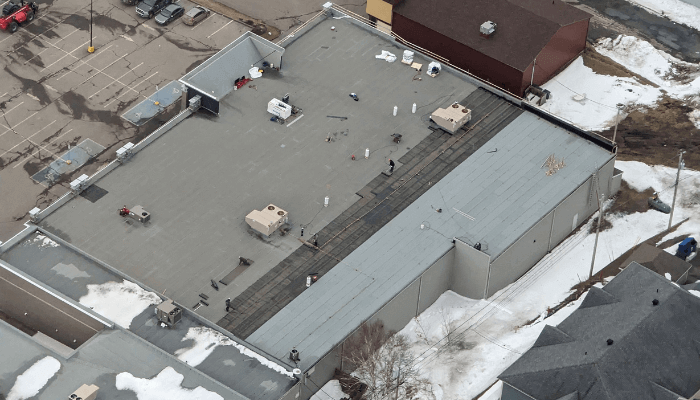 Une toiture plate de bâtiment commercial sur laquelle des couvreurs travaillent